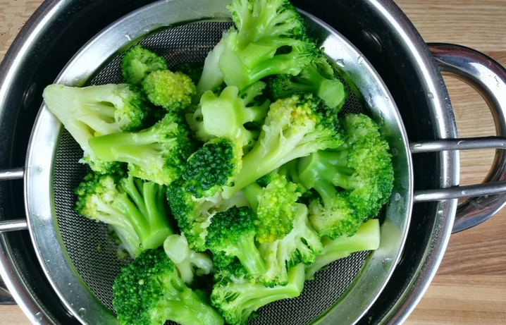 Frysta broccoli aldeende i vatten efter kokning i en kastrull